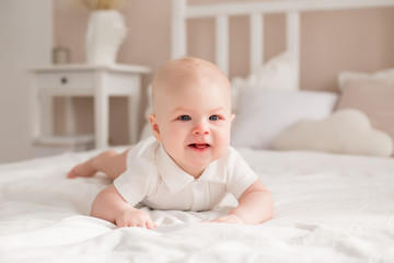 Cute toddler 6 months lies on the bed smiling
