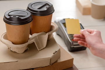 Two coffee cups and pizza boxes. Man paying for purchased take-away food
