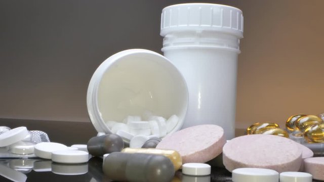 treatment concept, medicines in packs and jars and pills scattered on a black table