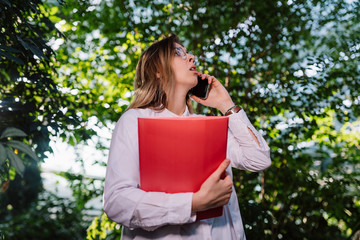 Fototapeta premium Young female agricultural engineer makes a call in greenhouse.