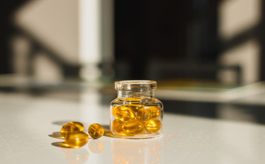 Cod liver capsules in glass bottle isolated on table
