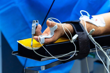 Hand of a patient lying on the operating table. Pulse oximeter sensor on the finger. The patient is...