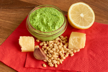 Pesto sauce with ingredients on wooden and red background