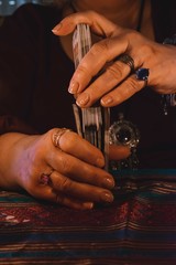 Woman's hands mixing a tarot card maze with jewelery on her fingers. Occultism concept