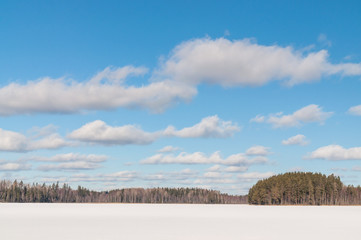 winter landscape with a frozen lake and clouds above it