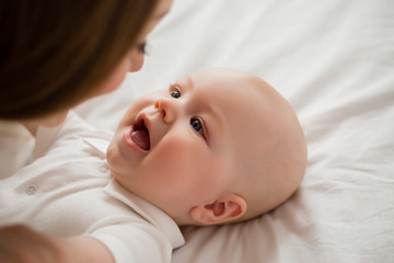 Happy young mother hugs toddler at home on bed