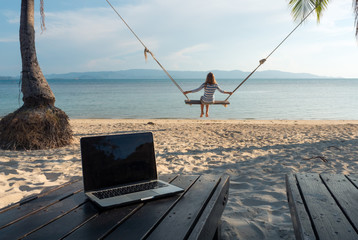 Woman after freelance work on the swing at tropical island sand beach line