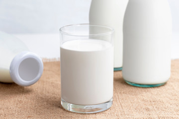 Bottle of milk and a glass of milk on the sackcloth with white background for food and healthy concept.