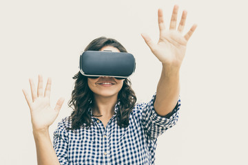 Happy student girl in VR goggles touching air. Young woman in virtual reality headset standing isolated over white background. VR experience concept