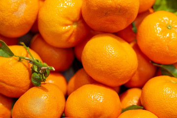 A pile of ripe oranges on a store counter. Many oranges are laid out on a display case, close-up.
