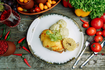 Restaurant dish with vegetable decor on a wooden background. Sea fish fried on a plate with sauce.