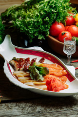 Restaurant dish with vegetable decor on a wooden background. Set of salted fish cut into slices on a plate.
