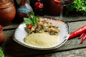 Restaurant dish with vegetable decor on a wooden background. Mashed potatoes with chicken and mushrooms.