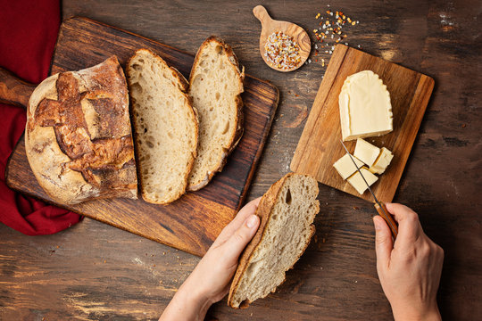 Woman Hands Cut Fresh Organic Artisan Bread. Healthy Eating, Buy Local, Homemade Bread Recipes Concept. Top View, Flat Lay