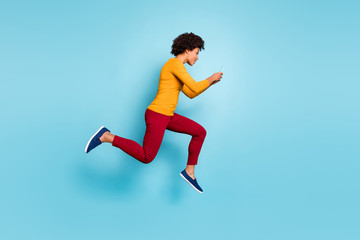 Full length body size view of her she nice attractive lovely addicted focused wavy-haired girl jumping running fast hurry rush using cell isolated on bright vivid shine vibrant blue color background