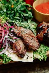  Restaurant dish with vegetable decor on a wooden background. Set of skewers with greens on a wooden Board.