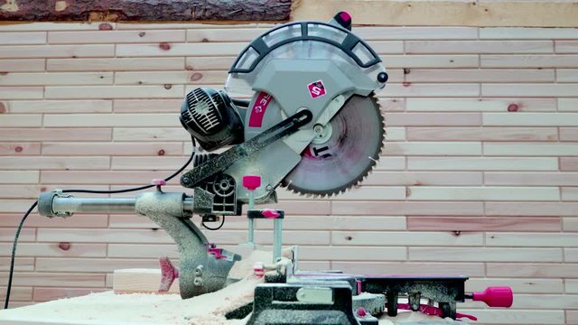 Wood sawing machine on a wooden wall background