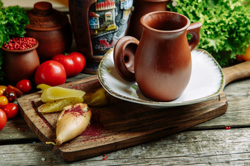 Azerbaijani restaurant dish with vegetable decor on a wooden background. Soup in a clay pot with herbs.