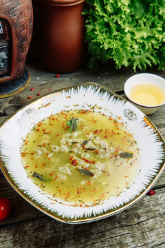 Azerbaijani restaurant dish with vegetable decor on a wooden background. Yellow soup dushbara in the plate of dumplings.