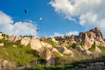 Fototapeta na wymiar Uchisar Old Town is a limestone mountain, with houses and balloons in the morning in Cappadocia, Turkey. This spot is popular with tourists.
