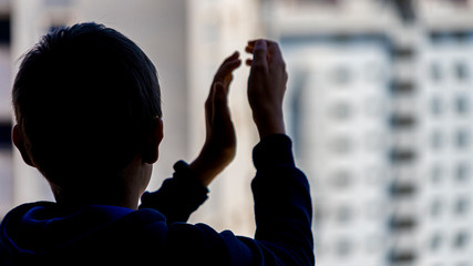 Kid applauding medical staff from their balcony. People in Spain clapping gratitude on balconies and windows in support of health workers, doctors and nurses during the Coronavirus pandemic