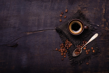 seen from above. On the rough and dark wooden table, a cup of coffee with a spoonful of coffee...