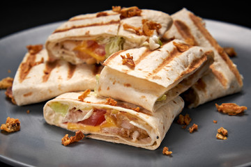 Shawarma sandwich - fresh roll of thin lavash or pita bread filled with grilled meat, vegetables, sauce, green. Traditional Eastern snack. On a Wooden Background