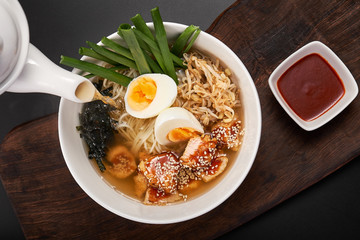 Traditional Korean (Japanese) ramen soup with chicken, egg, chives and sprout on dark wooden background