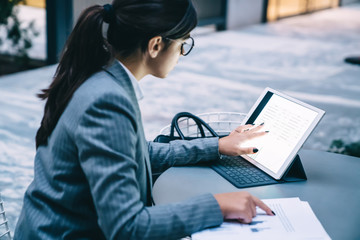 Concentrated Spanish woman in elegant outfit reading received email from business assistant with information about schedule for next week using public internet connection on modern portable pc