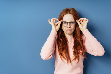 Grumpy young woman adjusting her glasses