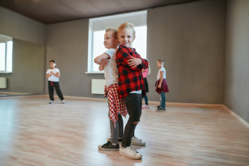 Little dancers. Two fashionable boys are standing back to back and looking at camera with smile...