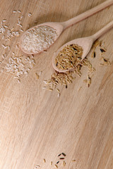 Background texture of grains of different rice. Top view on dry rice in spoons on a wooden table. Close up, vertical, place for text. The concept of a healthy diet and agriculture.