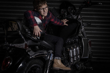 Fototapeta na wymiar BOY PLAYS WITH TOOL AND POSES ON THE MOTORBIKE IN THE GARAGE
