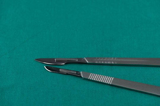 Basic surgical instrument, scalpel with sharp blade on surgical green drape fabric in operation room