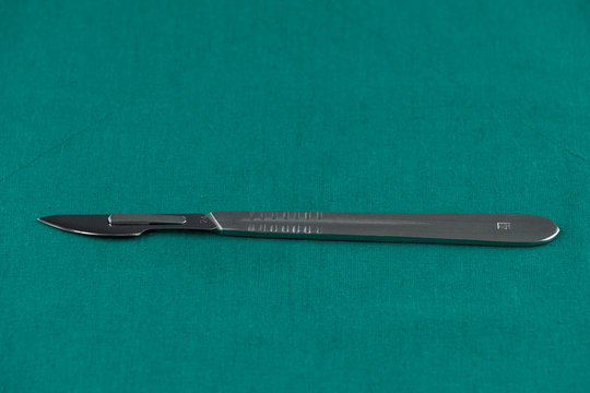 Basic surgical instrument, scalpel with sharp blade on surgical green drape fabric in operation room