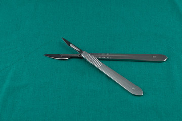 Basic surgical instrument, scalpel with sharp blade on surgical green drape fabric in operation room