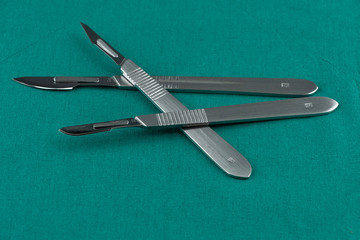 Basic surgical instrument, scalpel with sharp blade on surgical green drape fabric in operation room