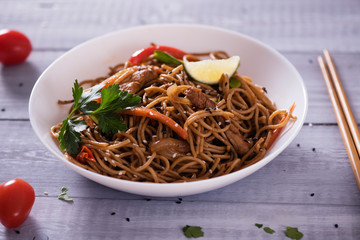 Japanese dish buckwheat noodles soba with chicken and vegetables carrots, bell peppers, mushrooms, green onions