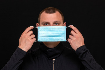 a man puts on a medical mask on his face, instructions on how to wear a mask