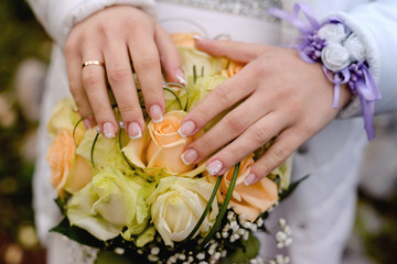 Obraz na płótnie Canvas hands with a ring on a bouquet of white roses