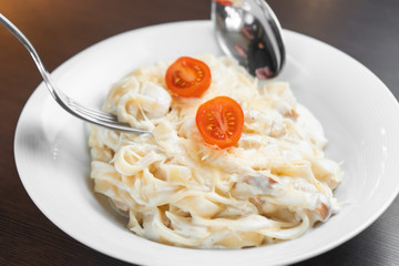 Pasta Carbonara is going to eat a man with a fork and spoon.
