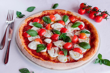 italian pizza margherita with tomato and basil on a white table