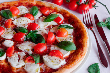 italian pizza margherita with tomato and basil on a white table