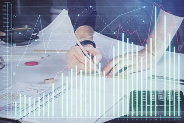 Double exposure of man writing on paper with forex graph.