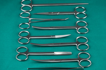 Basic surgical instrument scalpel forceps tweezers scissors on surgical green drape fabric in operation room