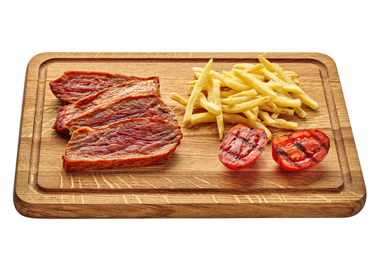Gourmet medium rare beefsteak with French fries and grilled cherry tomatoes on a cutting board with sauce isolated on white background.