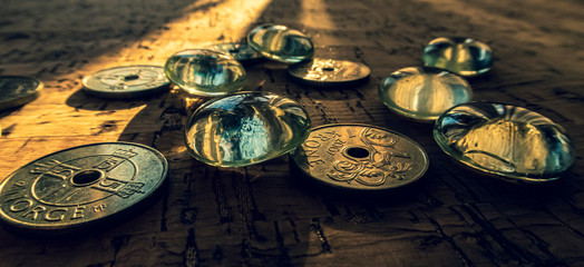 Closeup of a pile of Norwegian money on a cork background, illuminated by a beam of sunlight.
