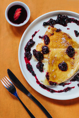 pancakes with raspberry and strawberry jam on an orange background