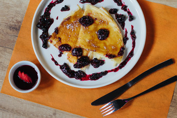 pancakes with raspberry and strawberry jam on an orange background