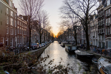Fototapeta premium One of the water channels in Amsterdam, with a church on the background under the sunset